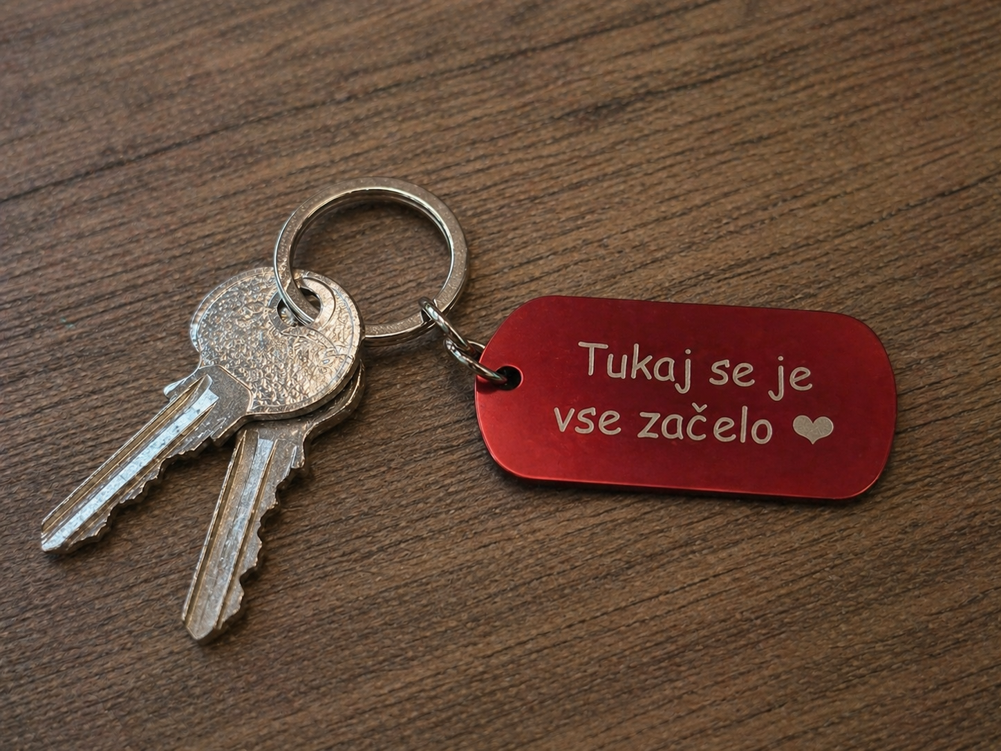 Obesek za ključe z gravuro Tukaj se je vse začelo pritrjen na ključe na lesenem ozadju – darilo za par ali obletnico