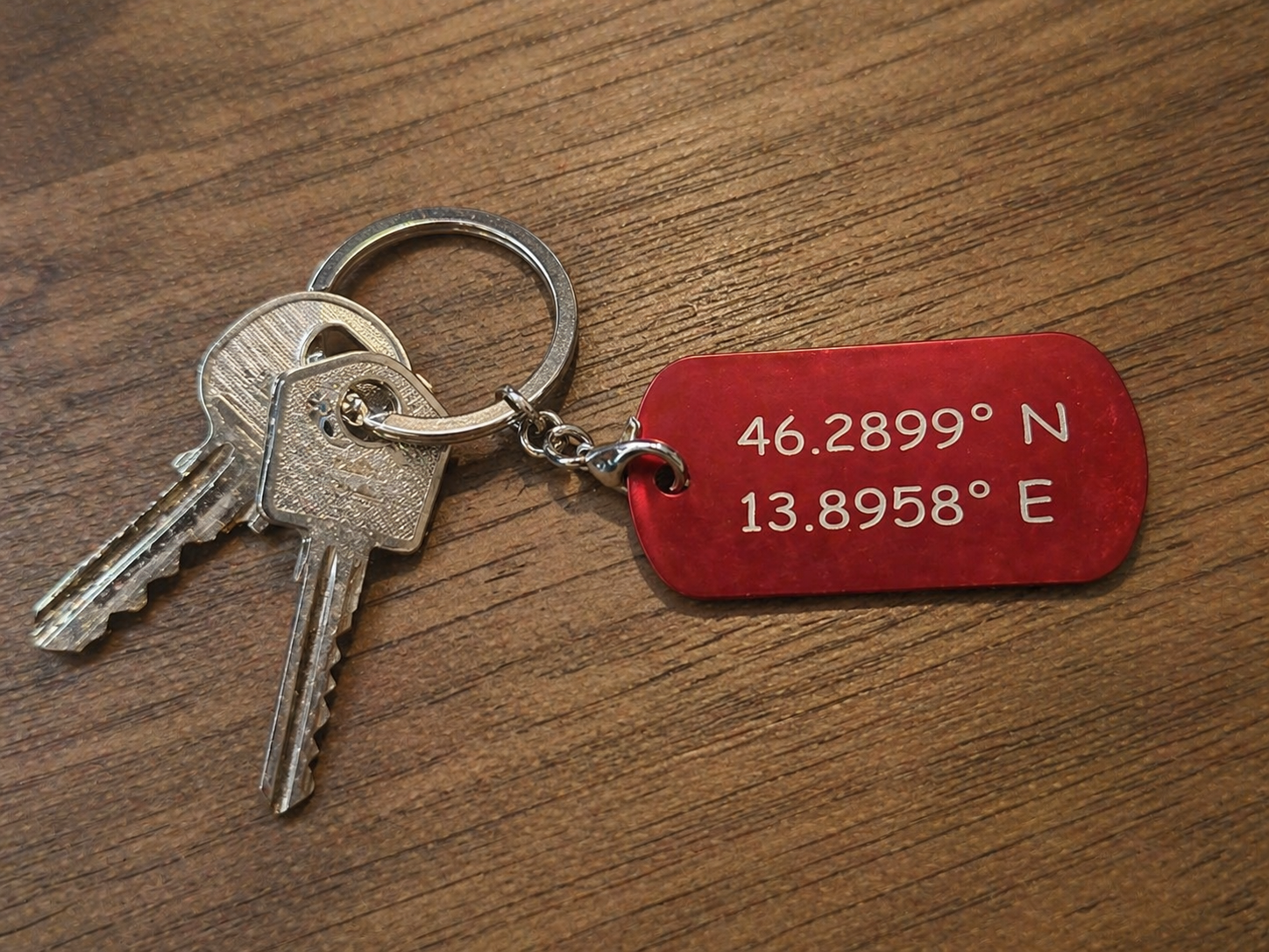Graviran rdeč kovinski obesek za ključe z koordinatami